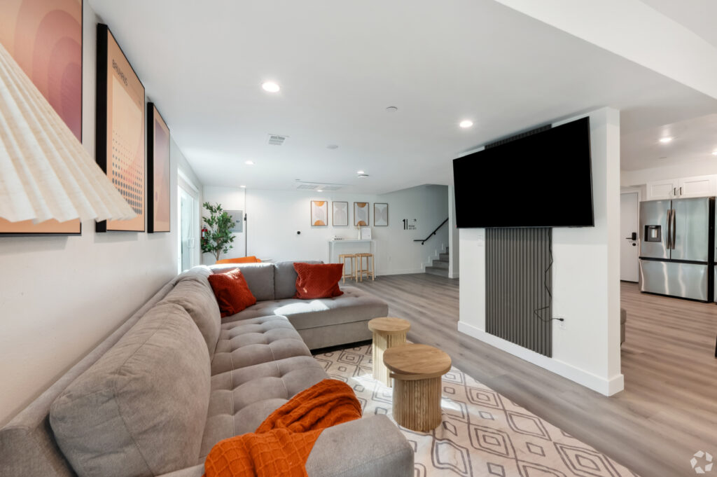 Modern living room with spacious sectional couch and large TV at Nest Housing near USC.